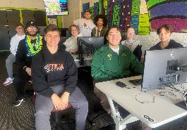  Esports club members pose for picture, some sitting others standing in classroom with computers